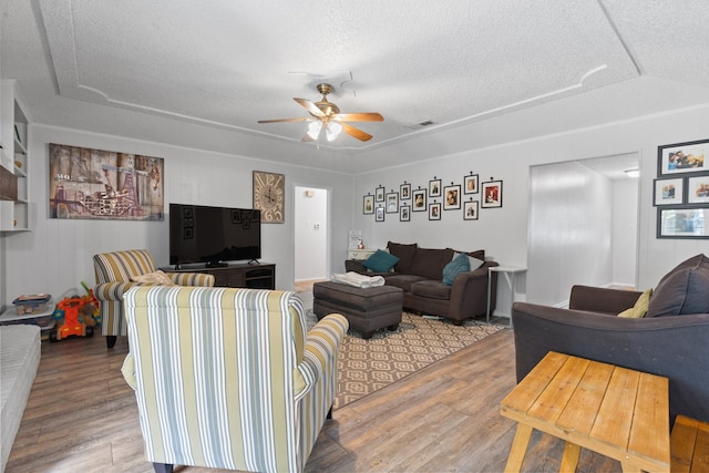 living room with a textured ceiling, ceiling fan, and hardwood / wood-style flooring