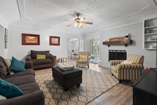 living room featuring ceiling fan, french doors, a textured ceiling, a fireplace, and dark hardwood / wood-style flooring