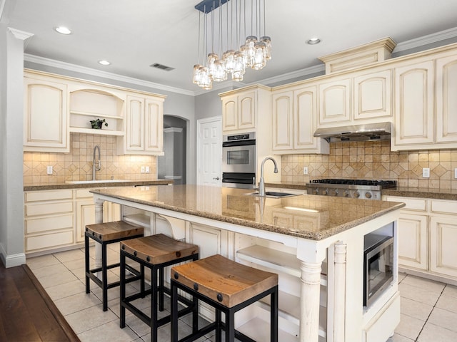 kitchen with decorative light fixtures, sink, ventilation hood, appliances with stainless steel finishes, and cream cabinetry