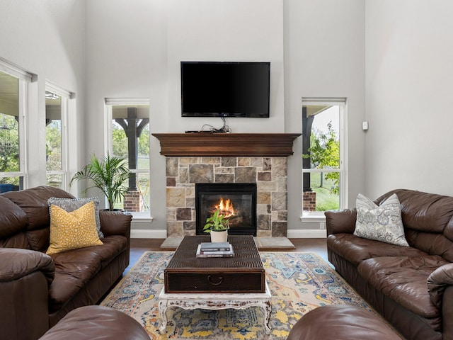 living room featuring a fireplace, a wealth of natural light, dark wood-type flooring, and a high ceiling