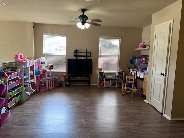 game room with dark wood-type flooring, a healthy amount of sunlight, and ceiling fan