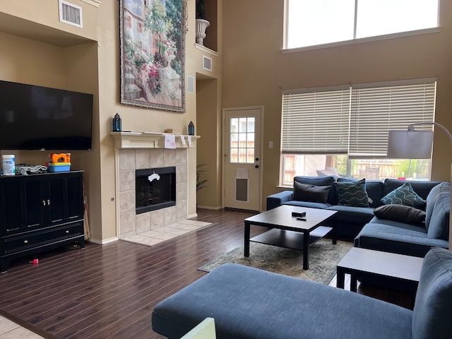 living room with a fireplace, dark hardwood / wood-style flooring, and a high ceiling