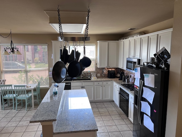 kitchen with decorative backsplash, hanging light fixtures, black appliances, light tile patterned floors, and white cabinets