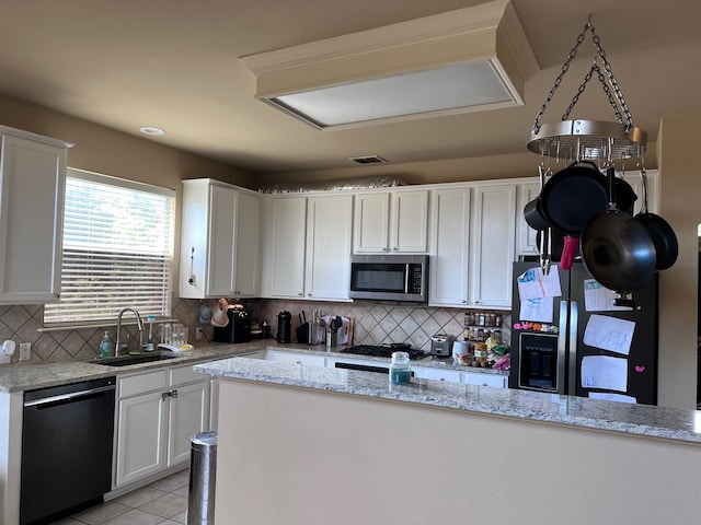 kitchen with backsplash, white cabinetry, light stone countertops, sink, and stainless steel appliances