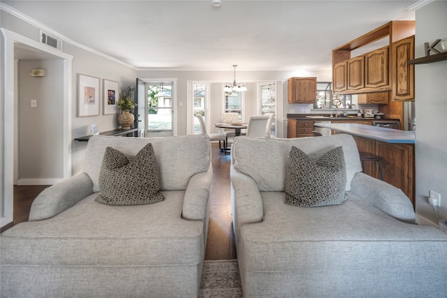 living room featuring crown molding, hardwood / wood-style floors, sink, and a notable chandelier