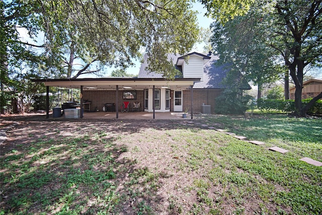 rear view of property featuring central air condition unit, a yard, a patio area, and a carport