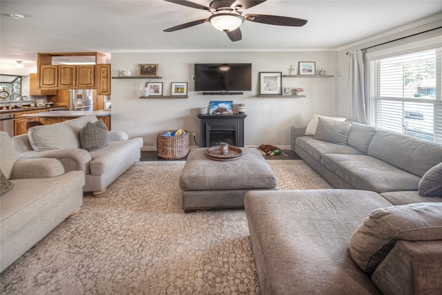 living room with ornamental molding and ceiling fan