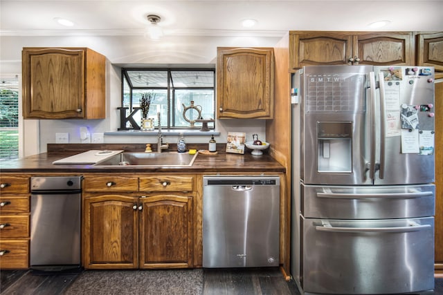 kitchen featuring ornamental molding, sink, stainless steel appliances, and dark wood-type flooring