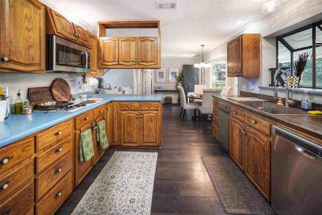 kitchen featuring appliances with stainless steel finishes, dark wood-type flooring, decorative light fixtures, sink, and a chandelier