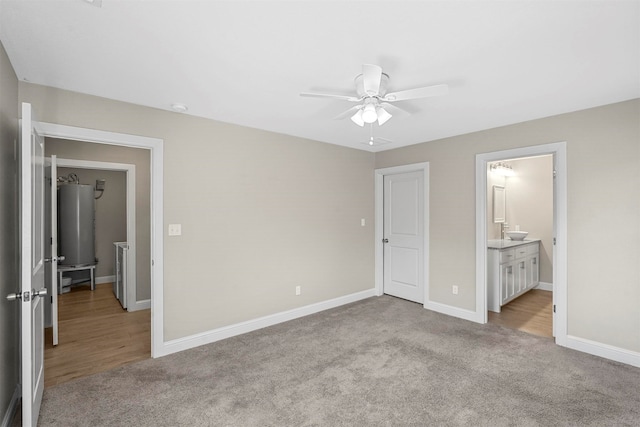 unfurnished bedroom with water heater, connected bathroom, ceiling fan, and light colored carpet