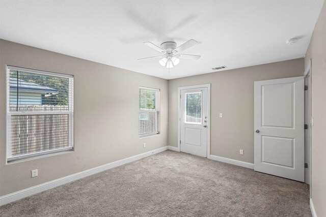 carpeted spare room featuring baseboards, ceiling fan, and visible vents