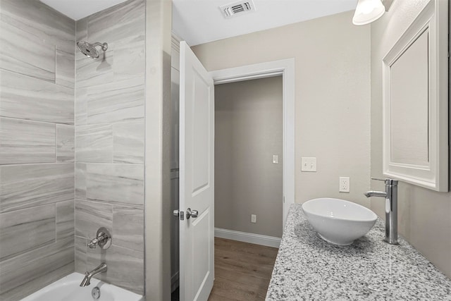 bathroom with vanity, tiled shower / bath, and hardwood / wood-style flooring