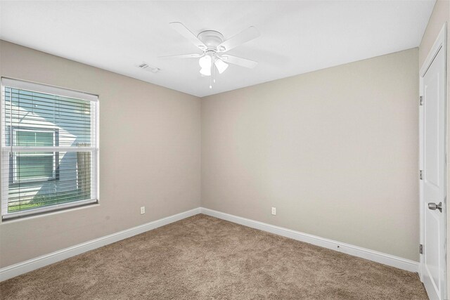 spare room with carpet flooring, a ceiling fan, baseboards, and visible vents