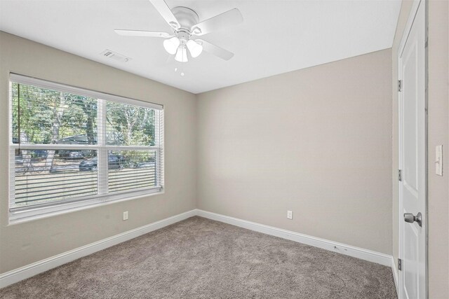 carpeted empty room with baseboards, visible vents, and ceiling fan