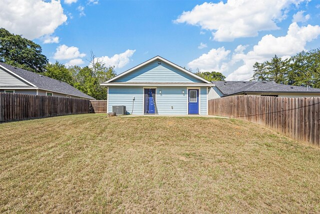 back of property with central AC, a yard, and a fenced backyard