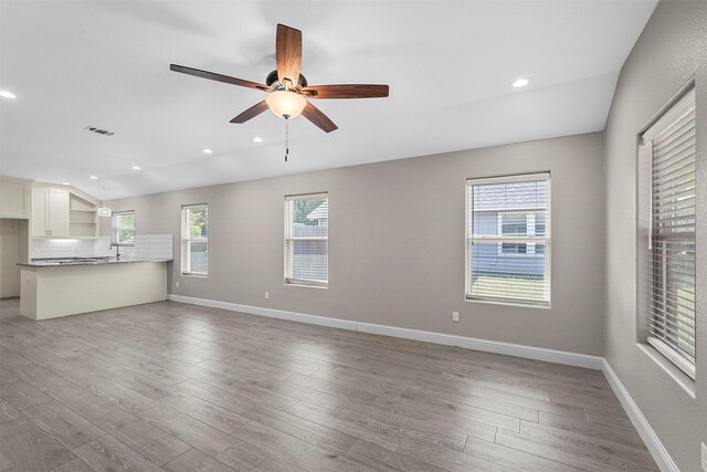 unfurnished living room featuring baseboards, visible vents, light wood-style flooring, and a ceiling fan