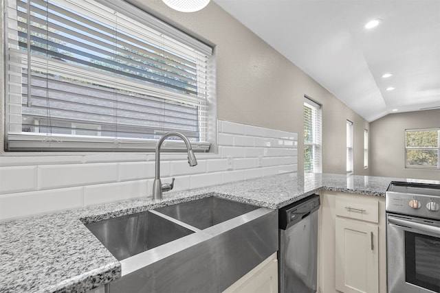 kitchen with light stone counters, sink, vaulted ceiling, white cabinetry, and appliances with stainless steel finishes