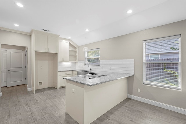 kitchen featuring kitchen peninsula, white cabinetry, light hardwood / wood-style flooring, and a wealth of natural light