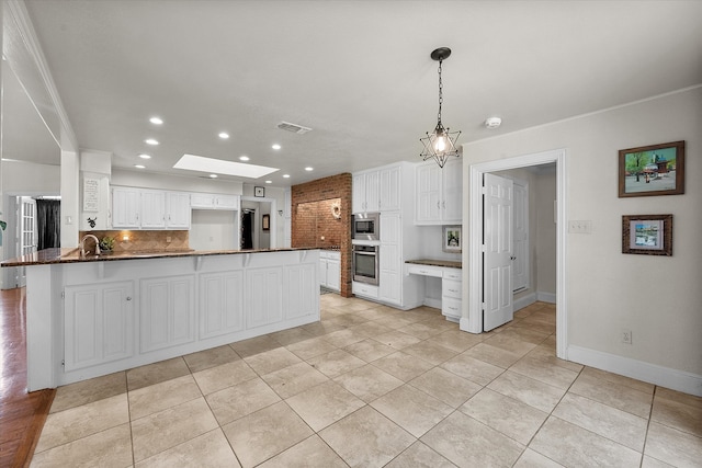 kitchen with white cabinetry, kitchen peninsula, appliances with stainless steel finishes, and a skylight