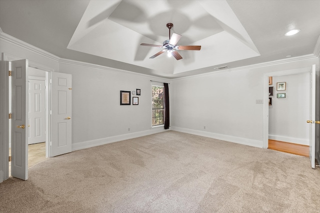 carpeted empty room featuring a tray ceiling, crown molding, and ceiling fan