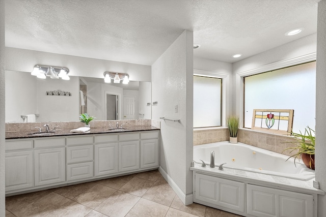 bathroom featuring a bathing tub, vanity, a textured ceiling, and tile patterned floors