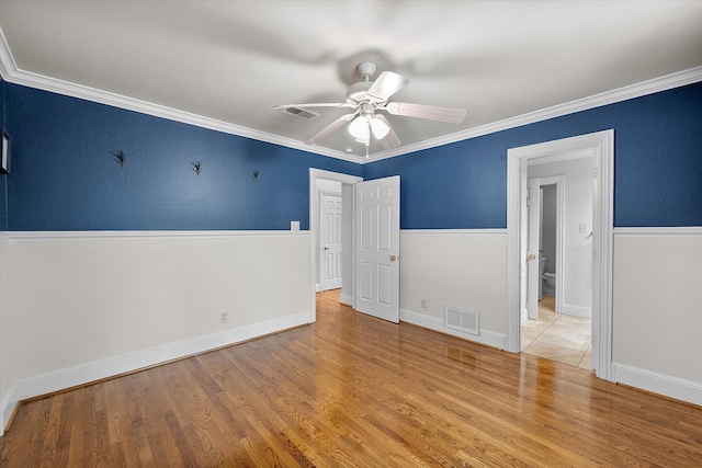 spare room featuring light wood-type flooring, ceiling fan, and crown molding