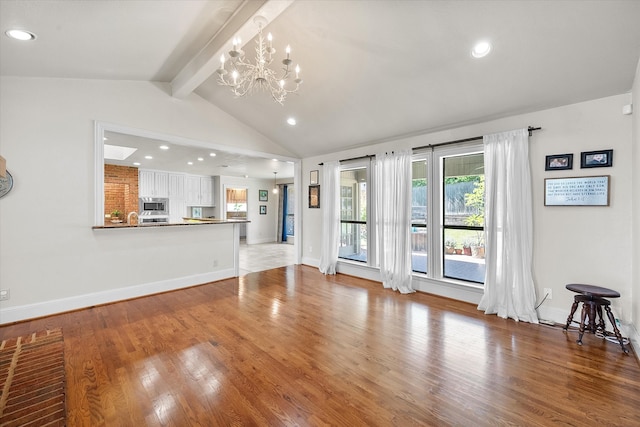 unfurnished living room with a chandelier, lofted ceiling with beams, and light hardwood / wood-style floors