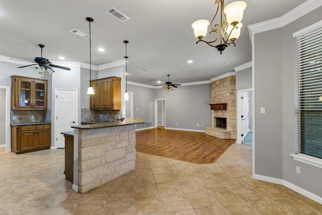 kitchen featuring tasteful backsplash, kitchen peninsula, hanging light fixtures, a fireplace, and ornamental molding