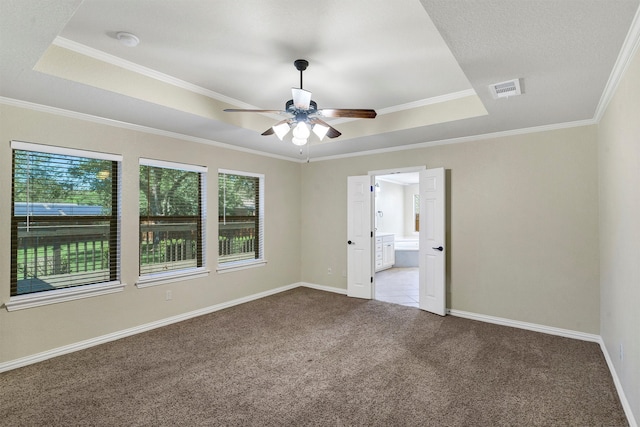 carpeted spare room with a raised ceiling, ornamental molding, and ceiling fan