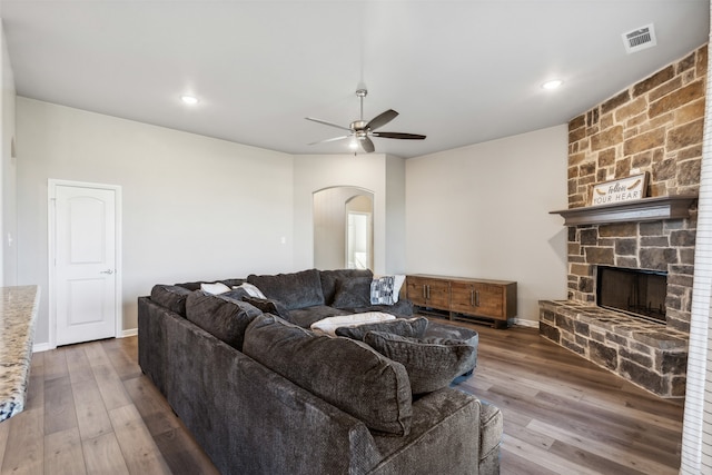 living room featuring ceiling fan, hardwood / wood-style flooring, and a fireplace