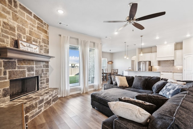 living room featuring ceiling fan, dark hardwood / wood-style floors, and a fireplace