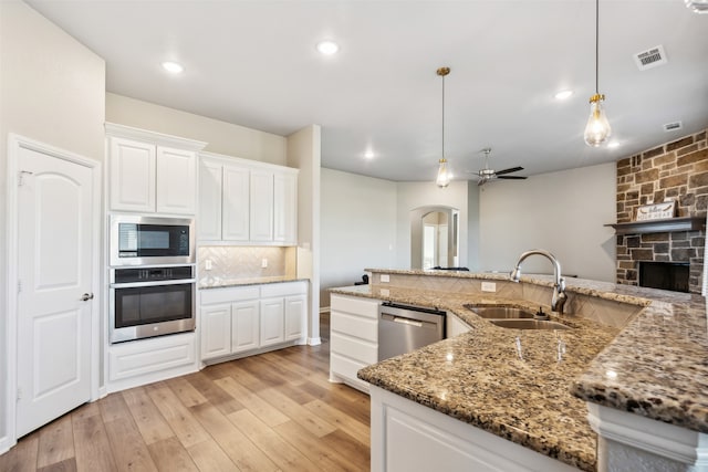 kitchen featuring white cabinets, a fireplace, stainless steel appliances, ceiling fan, and decorative light fixtures