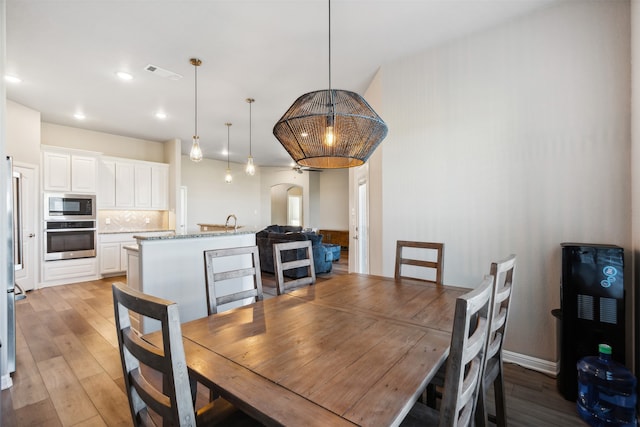 dining area featuring vaulted ceiling, light hardwood / wood-style floors, and sink