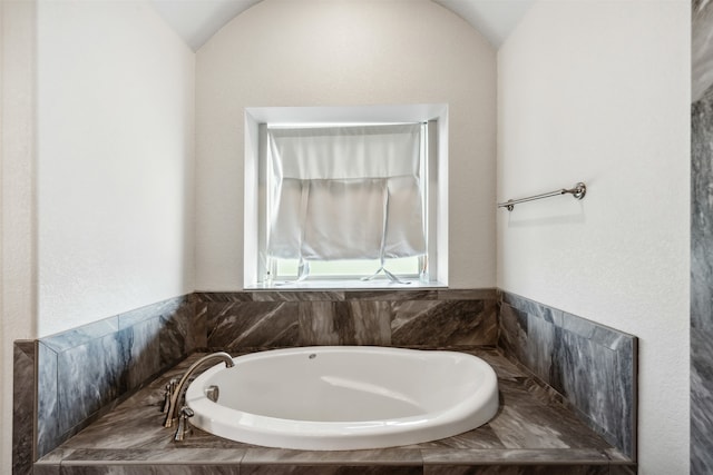 bathroom with a tub to relax in and vaulted ceiling