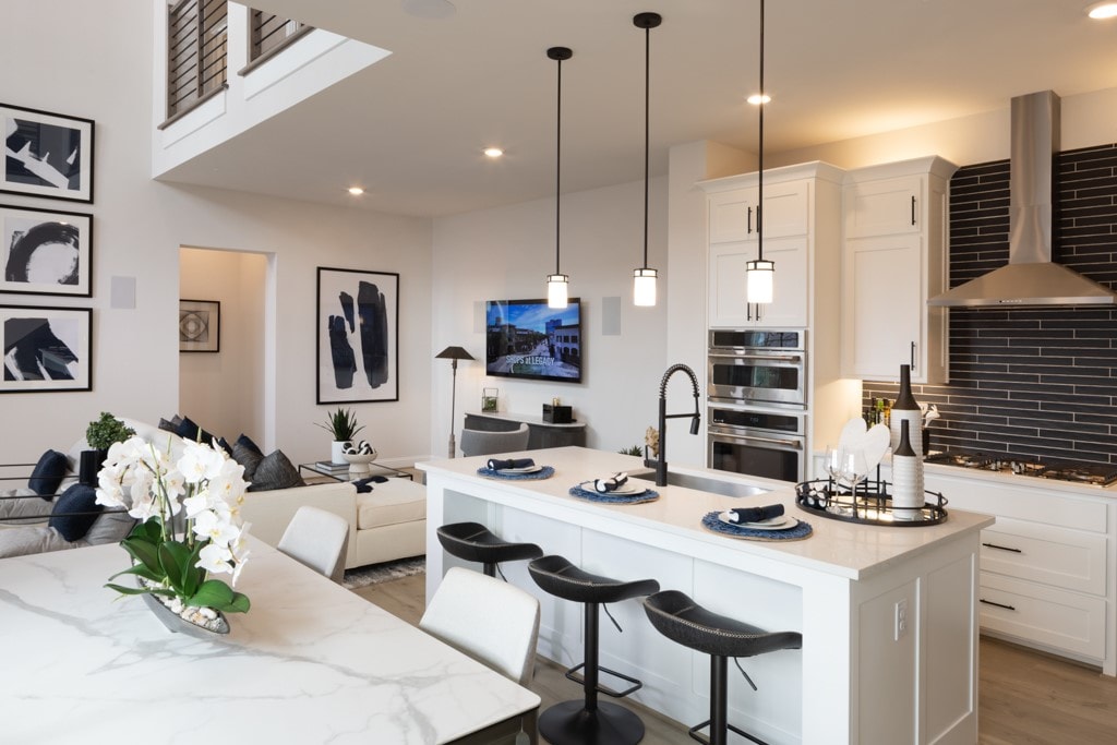 kitchen with wall chimney exhaust hood, tasteful backsplash, gas stovetop, and an island with sink