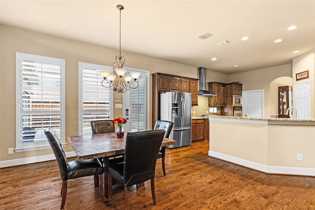 dining space with sink, a chandelier, and dark wood-type flooring