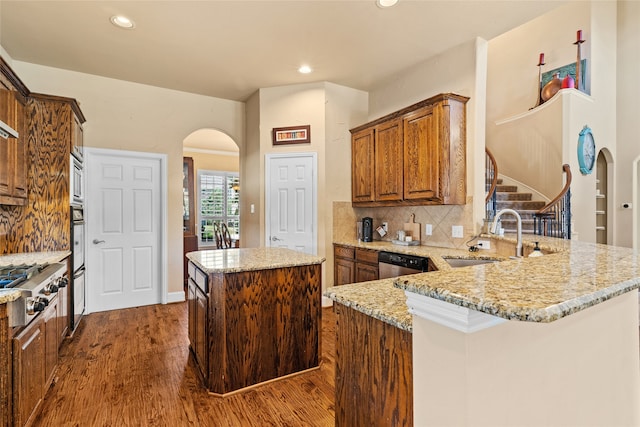 kitchen featuring a center island, sink, kitchen peninsula, backsplash, and dark hardwood / wood-style flooring