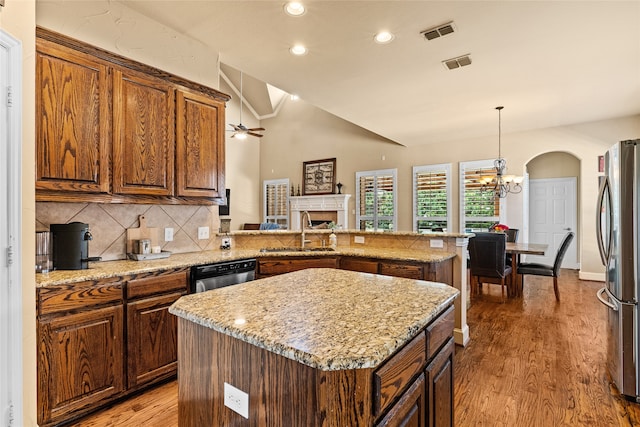 kitchen with sink, vaulted ceiling, stainless steel appliances, a center island, and hardwood / wood-style floors