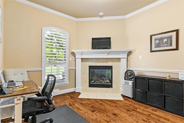 office area featuring ornamental molding, a tiled fireplace, and light hardwood / wood-style floors