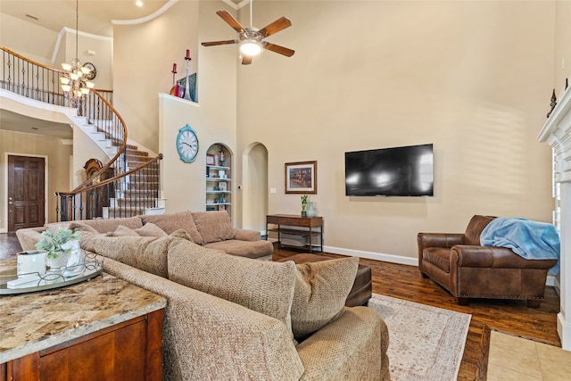 living room with ceiling fan with notable chandelier, a towering ceiling, and hardwood / wood-style floors