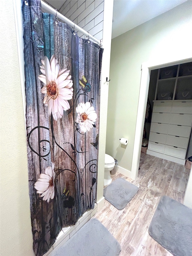 bathroom with wood-type flooring, walk in shower, and toilet