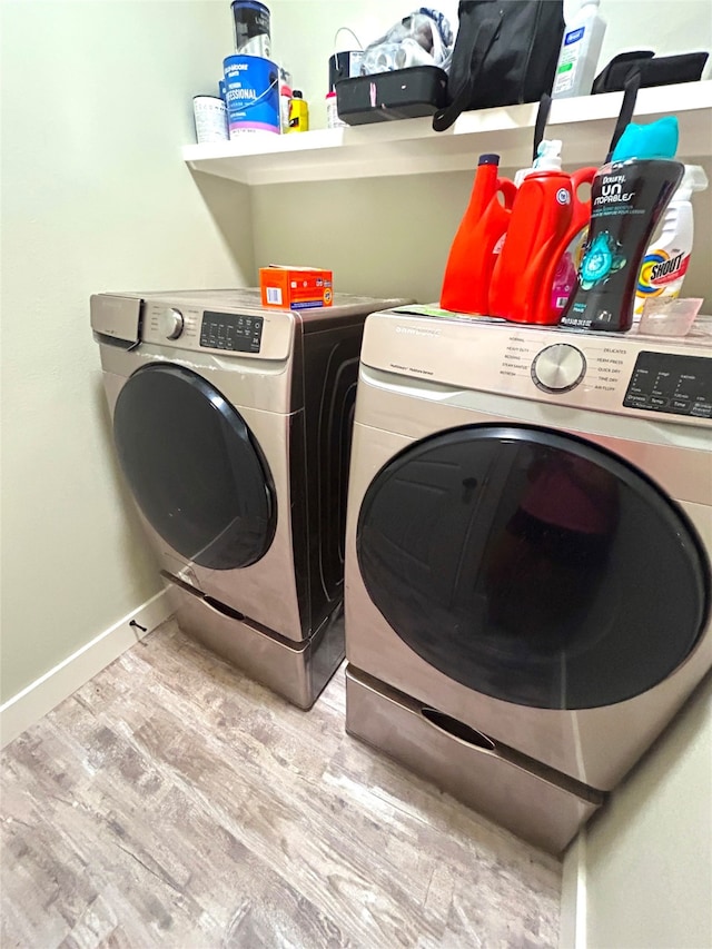 clothes washing area featuring washer and clothes dryer and light hardwood / wood-style floors