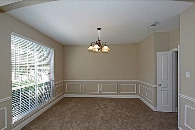 empty room featuring dark colored carpet and a chandelier