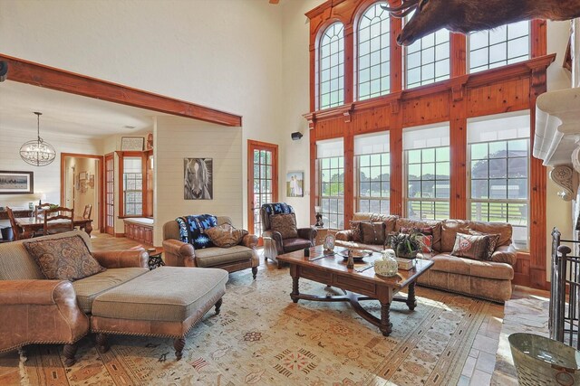 living room featuring a towering ceiling, an inviting chandelier, light hardwood / wood-style flooring, and plenty of natural light