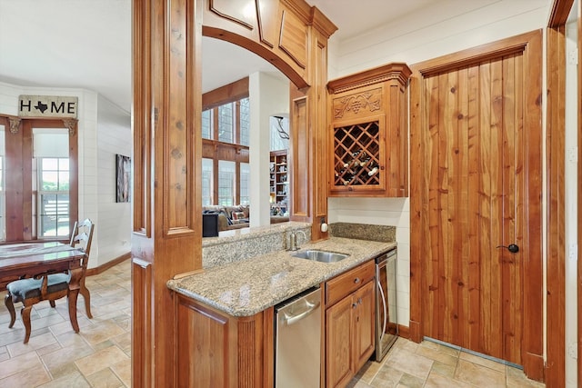 kitchen with a healthy amount of sunlight, stainless steel dishwasher, sink, and light stone counters