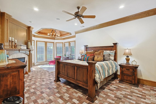 bedroom with ceiling fan with notable chandelier, a raised ceiling, ornamental molding, and a tile fireplace