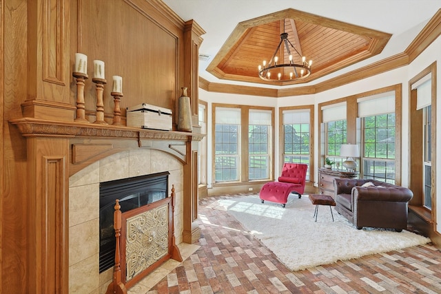 living room with wood walls, a tiled fireplace, a chandelier, a high ceiling, and crown molding