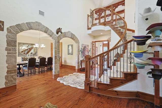 entryway featuring an inviting chandelier, crown molding, a towering ceiling, and hardwood / wood-style flooring