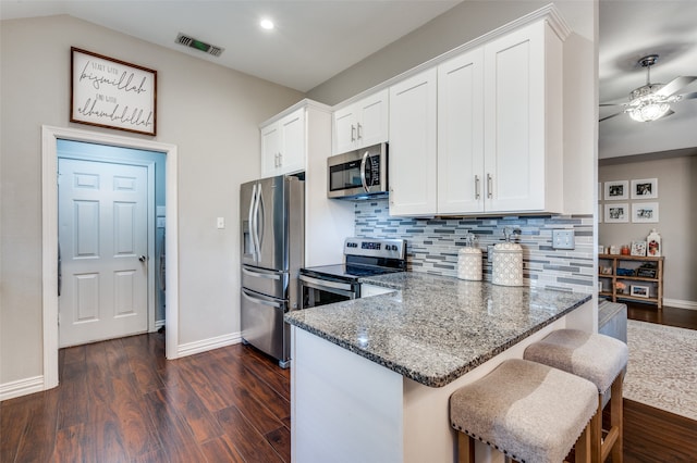 kitchen featuring ceiling fan, backsplash, white cabinetry, appliances with stainless steel finishes, and dark hardwood / wood-style floors