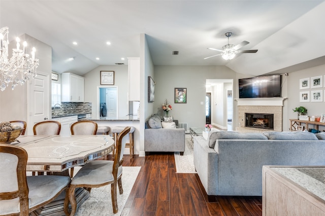 dining area featuring vaulted ceiling, ceiling fan with notable chandelier, and dark wood-type flooring